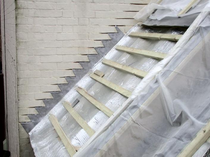A partially constructed roof, showing the battens and lead flashing.