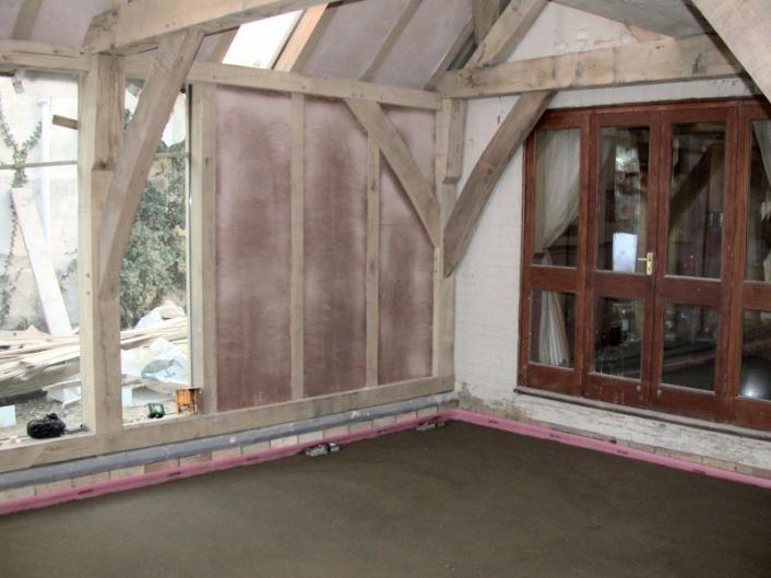 A newly screed and plastered extension during construction.