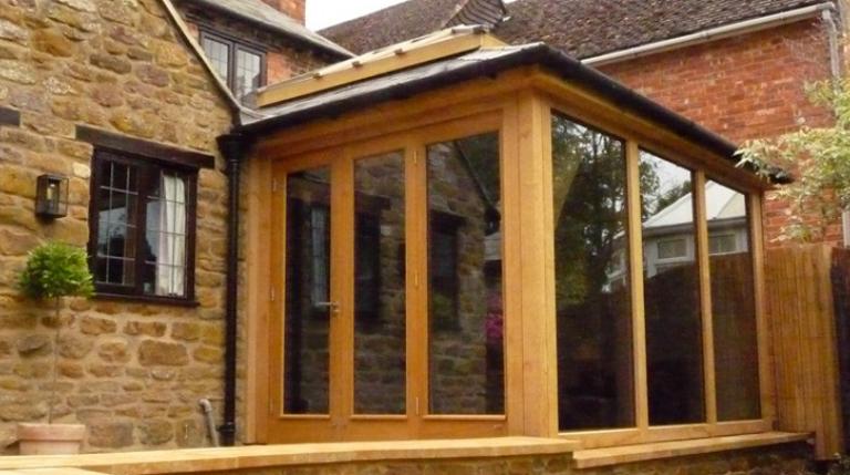 A modern oak framed extension sitting within an L-shaped building.