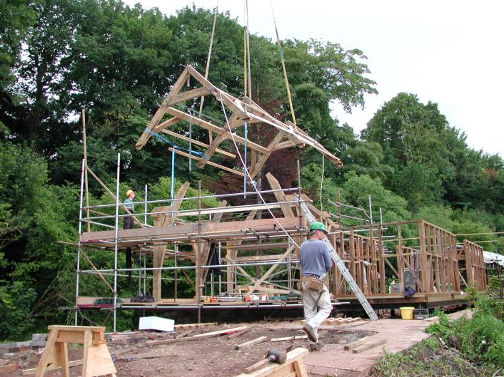An oak framed roof being lowered into place by crane.