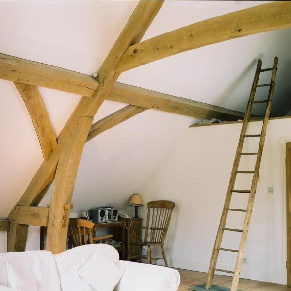 Exposed oak trusses with a ladder to the room in the roof.