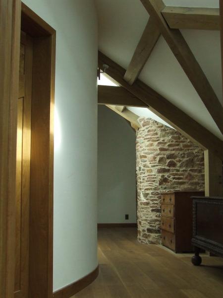 Curved corridor with exposed stone and oak beams.