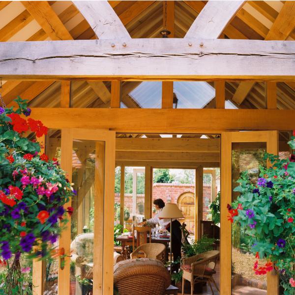 An oak framed garden room with hanging baskets.