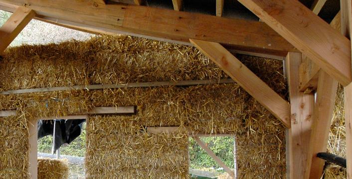 Straw bales being fitted to a Douglas fir frame to create an eco-house.