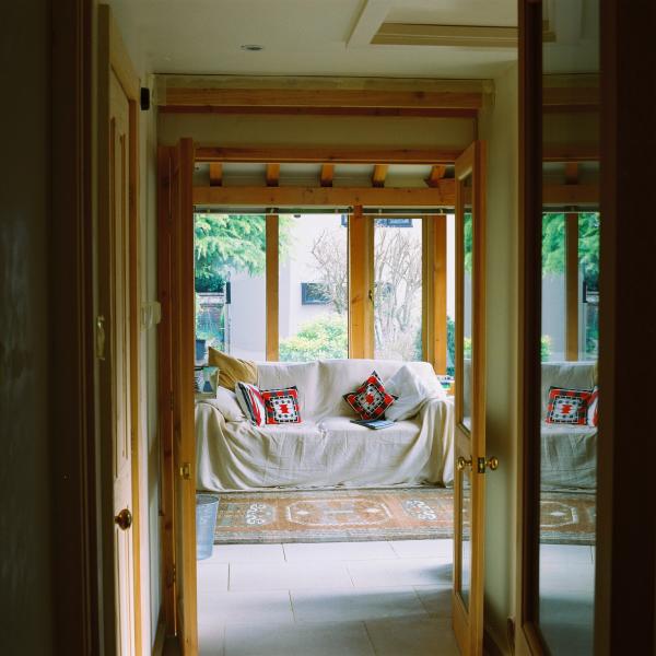 A white sofa through a doorway with windows behind in a Douglas fir studio.