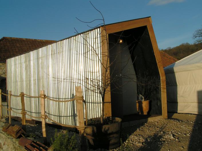 Timber structure part clad in larch and part clad in corrugated steel.